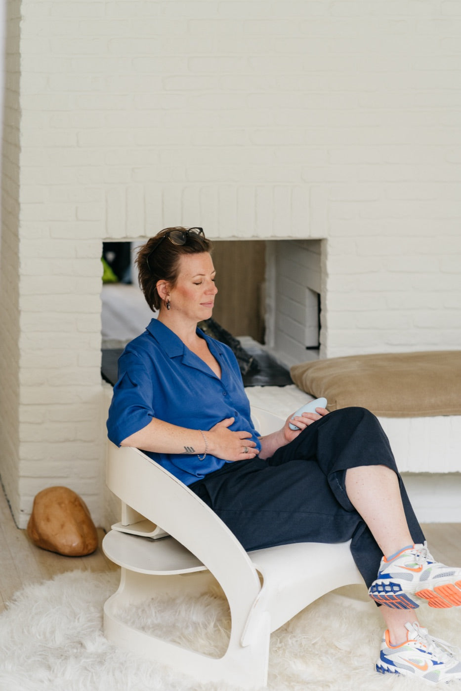 A woman in a blue shirt seated with her eyes closed, holding moonbird