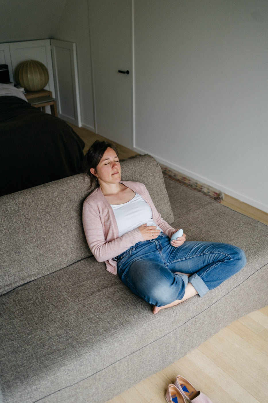 A woman resting on a sofa with her eyes closed, holding a light blue moonbird