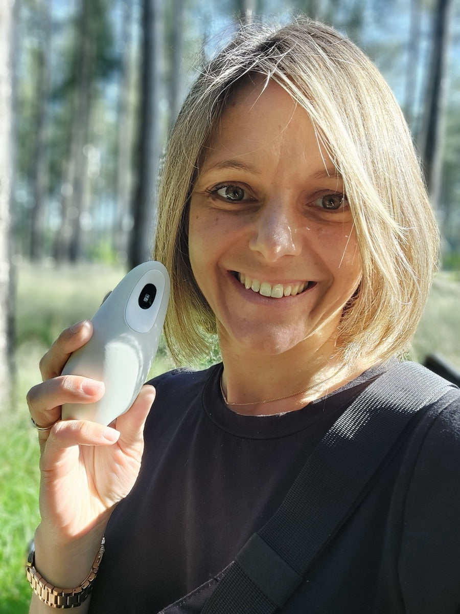 A woman outdoors holding a light-colored moonbird beside her face