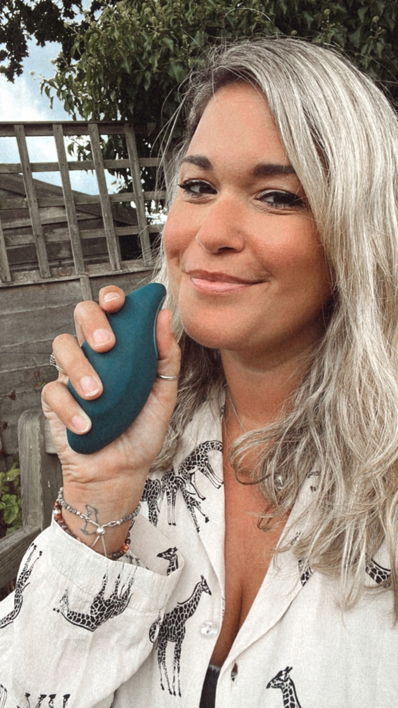A woman outdoors holding a teal moonbird in her hand