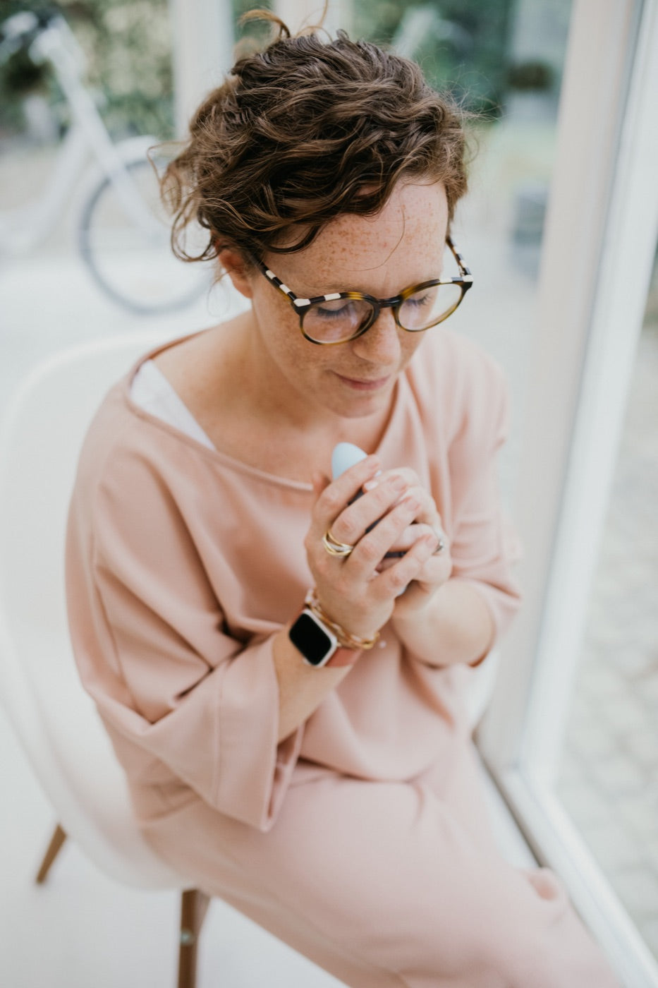 A woman seated by a window holding moonbird in both hands