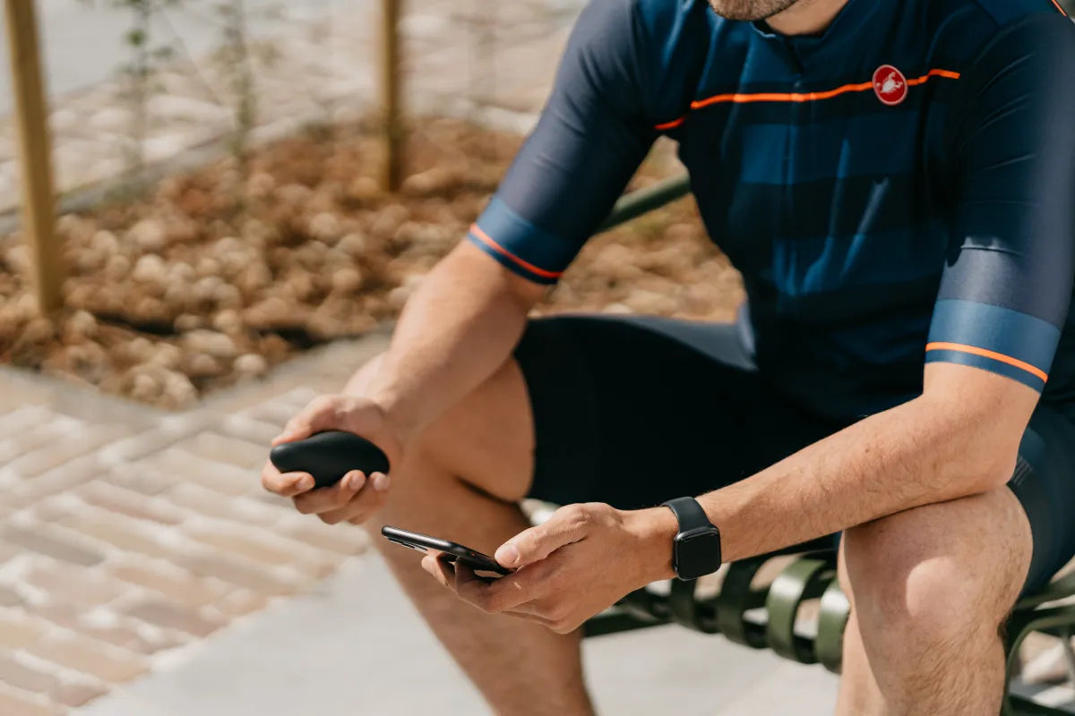 Cyclist after a ride holding moonbird in one hand and his phone in the other, sports watch on his wrist